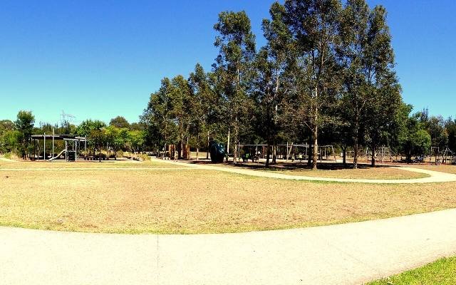 A curving path across open grass and eucalyptus trees in the Western Sydney Parklands