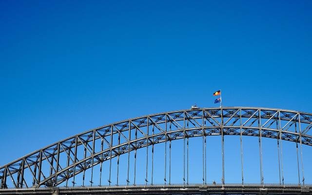 The steel arch of the Sydney Harbour Bridge with flags flying at the top