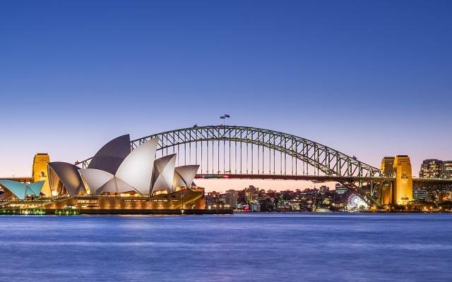 The Sydney Opera House and Harbour Bridge across the water at dusk