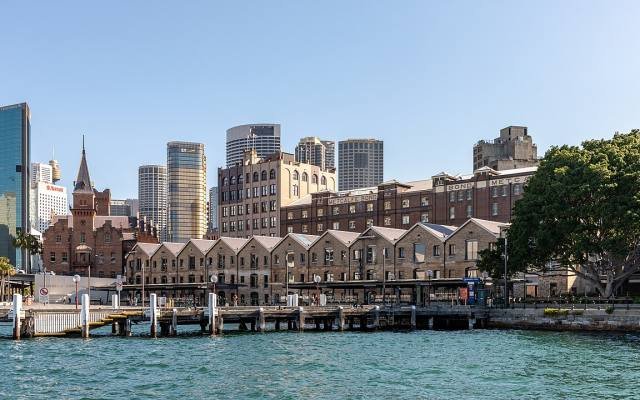 Historic sandstone warehouses of The Rocks on the waterfront with city towers behind